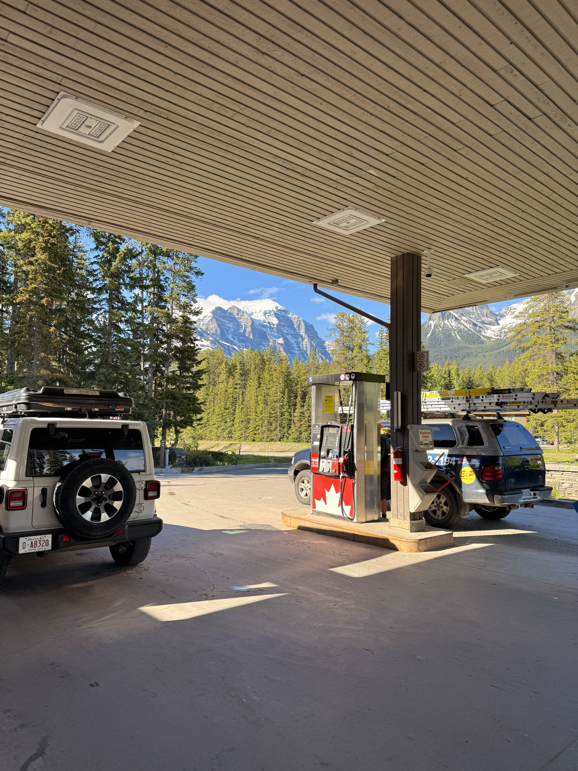 jeep at gas station with canadian flag and mountains