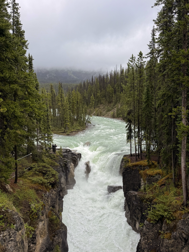 two people viewing a powerful waterfall in a Canadian forest