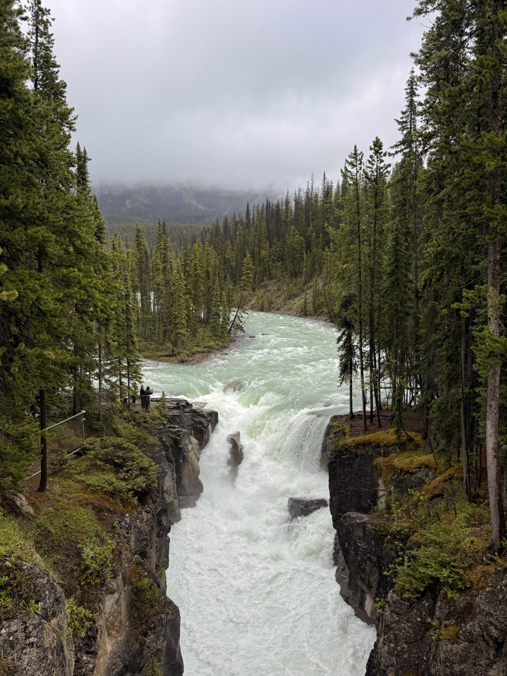 two people viewing a powerful waterfall in a Canadian forest