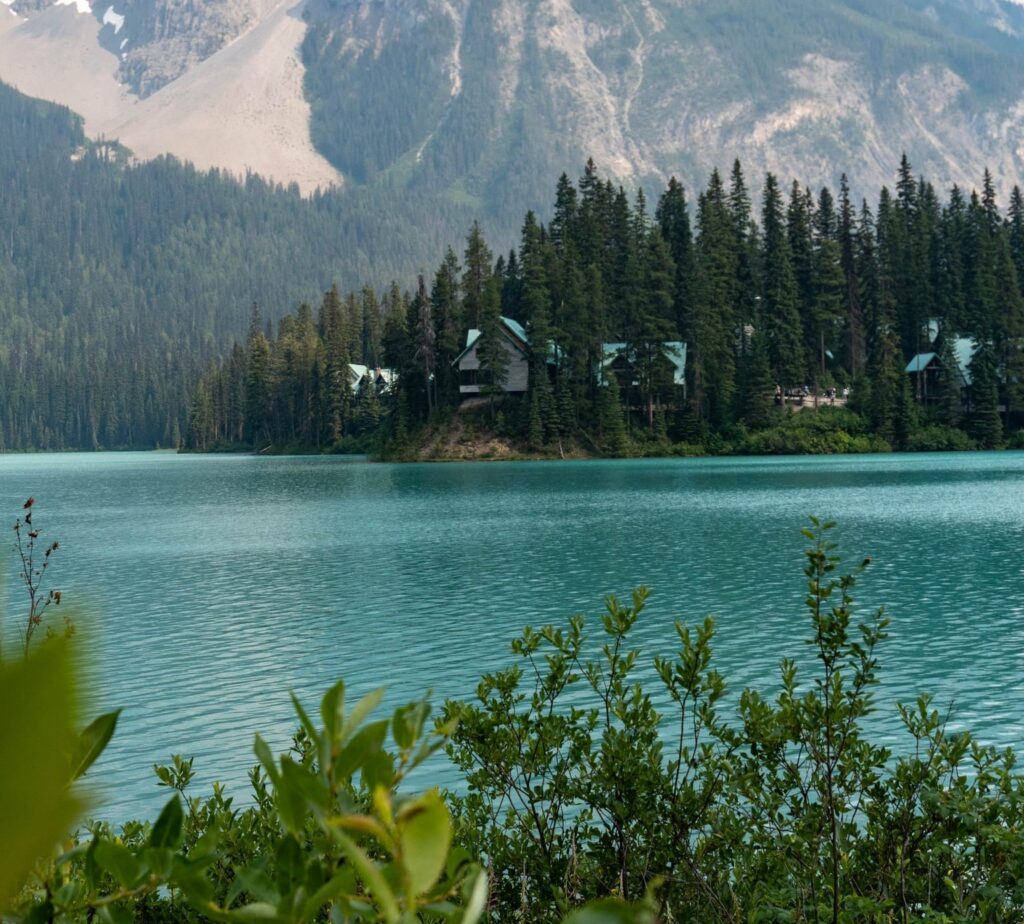emerald lake with cabins nestled in forest and mountains